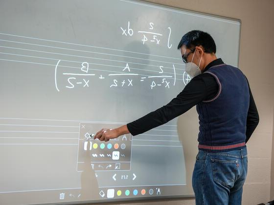 一个学生在白板上写方程式.